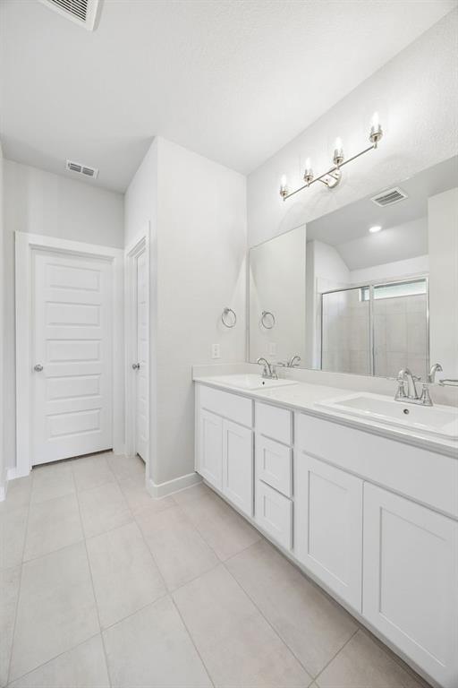 1448 Companero Street Haslet, TX 76052 - Photo 22 of 35 a bathroom with a double vanity sink a large mirror and a bathtub