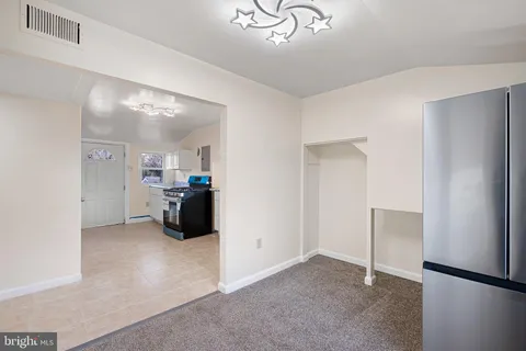 a living room with stainless steel appliances kitchen island a refrigerator and a sink