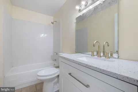 a bathroom with a granite countertop sink a toilet and a mirror