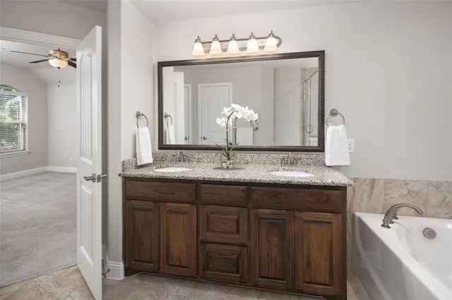 a bathroom with a granite countertop sink a large mirror and a bathtub