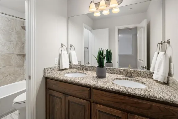 a bathroom with a granite countertop double vanity and a mirror
