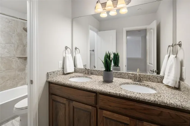 a bathroom with a granite countertop double vanity and a mirror