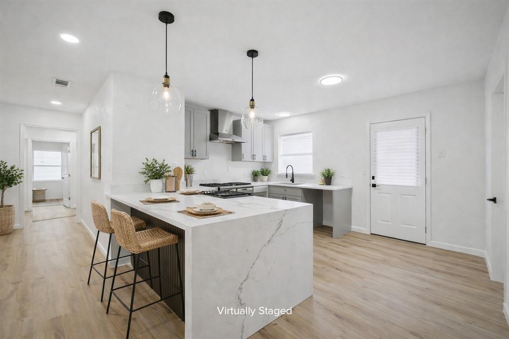 a kitchen with stainless steel appliances granite countertop a sink a stove a refrigerator and a dining table with wooden floor