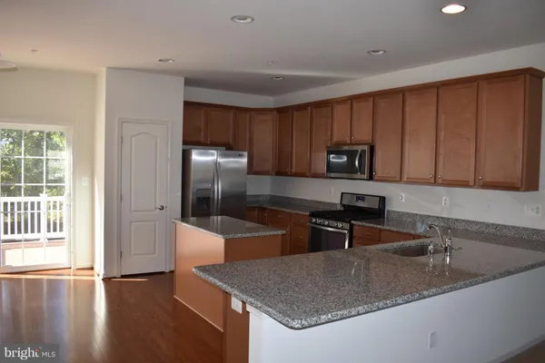 a kitchen with granite countertop a sink a stove and refrigerator