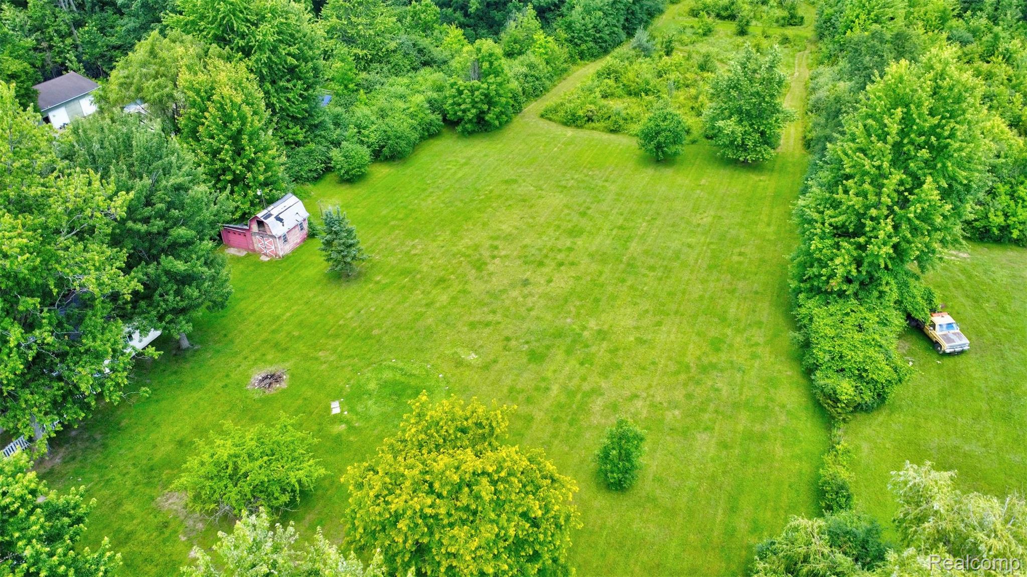 5244 Oleksyn Road Flint, MI 48504 - Photo 38 of 70 Expansive green lot featuring lush trees, a small shed structure, and an open grass area