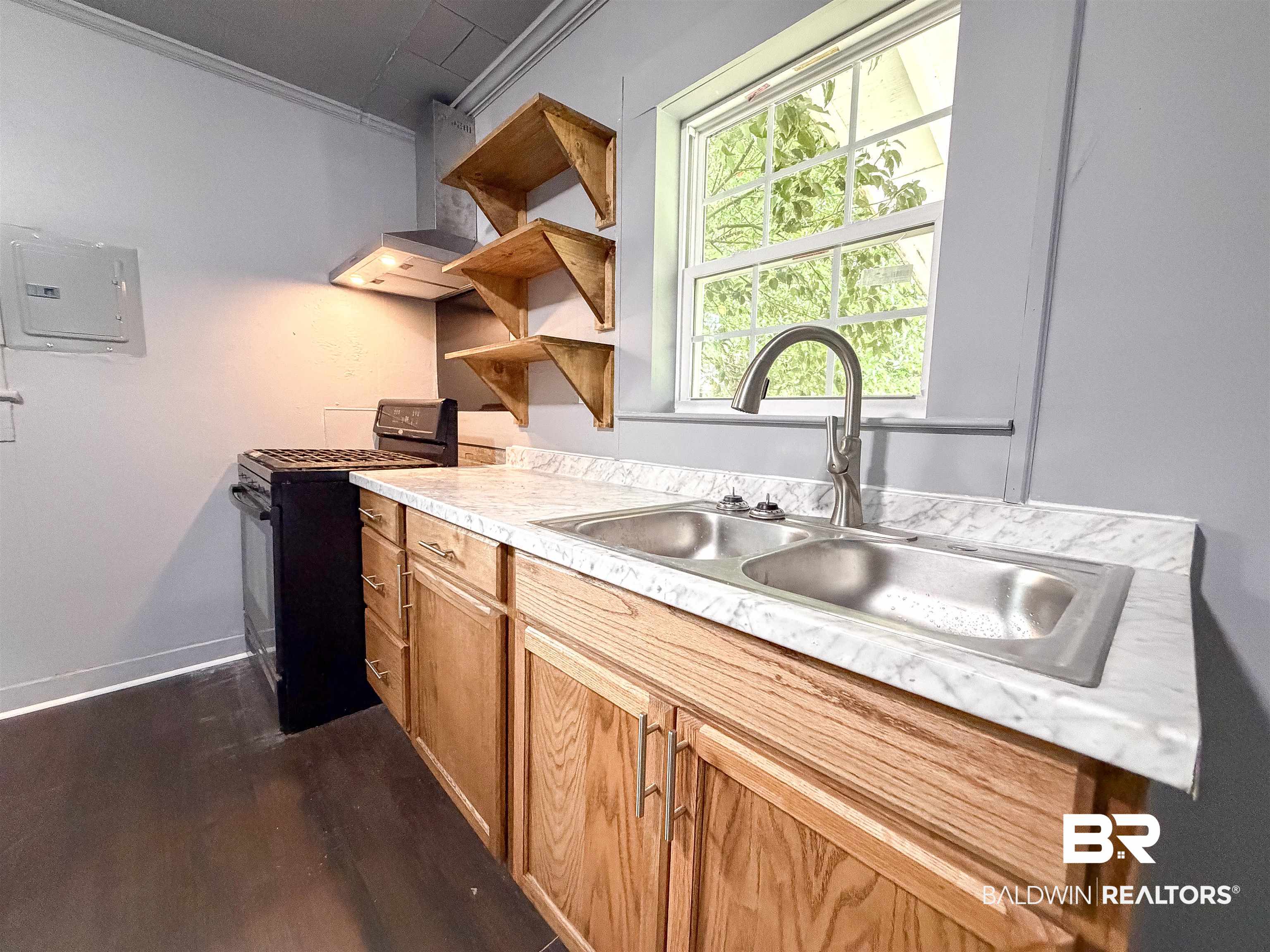 38 Flock Avenue Mobile, AL 36610 - Photo 6 of 27 Kitchen featuring wood cabinetry, a double basin stainless steel sink with a high-arc faucet, and light-toned countertops