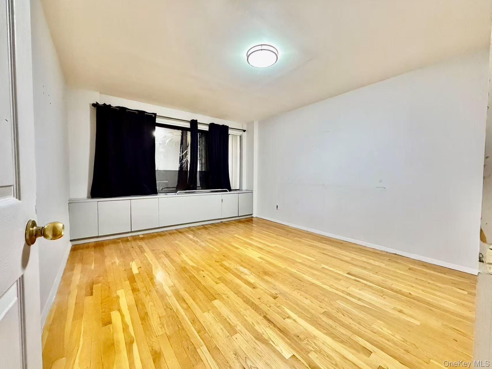87-14 57th Road, Unit 3B Queens, NY 11373 - Photo 6 of 14 a view of an empty room with wooden floor