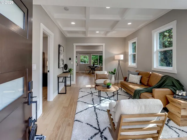 a living room with furniture two large windows and a wooden floor
