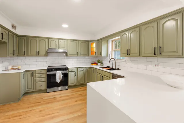 a kitchen with stainless steel appliances sink a stove and cabinets