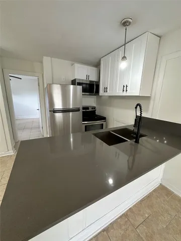 a kitchen with stainless steel appliances a refrigerator sink and white cabinets