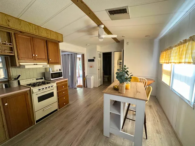 a kitchen with granite countertop wooden floors wooden cabinets and stainless steel appliances