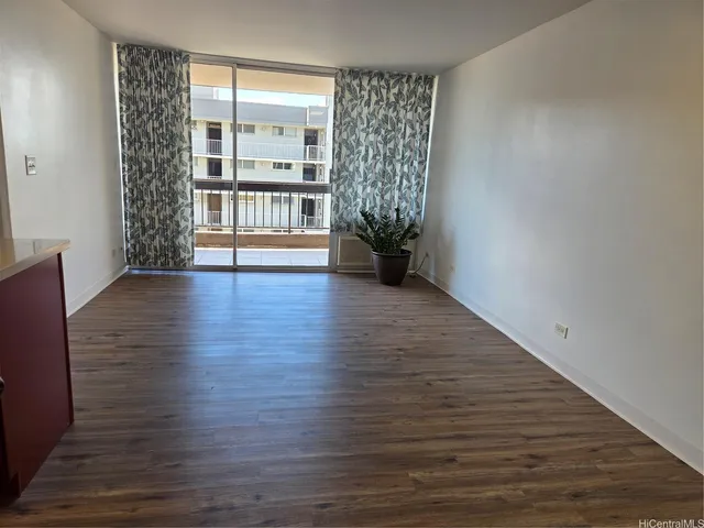 a view of an empty room with a window and wooden floor
