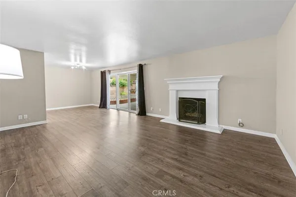 an empty room with wooden floor fireplace and windows