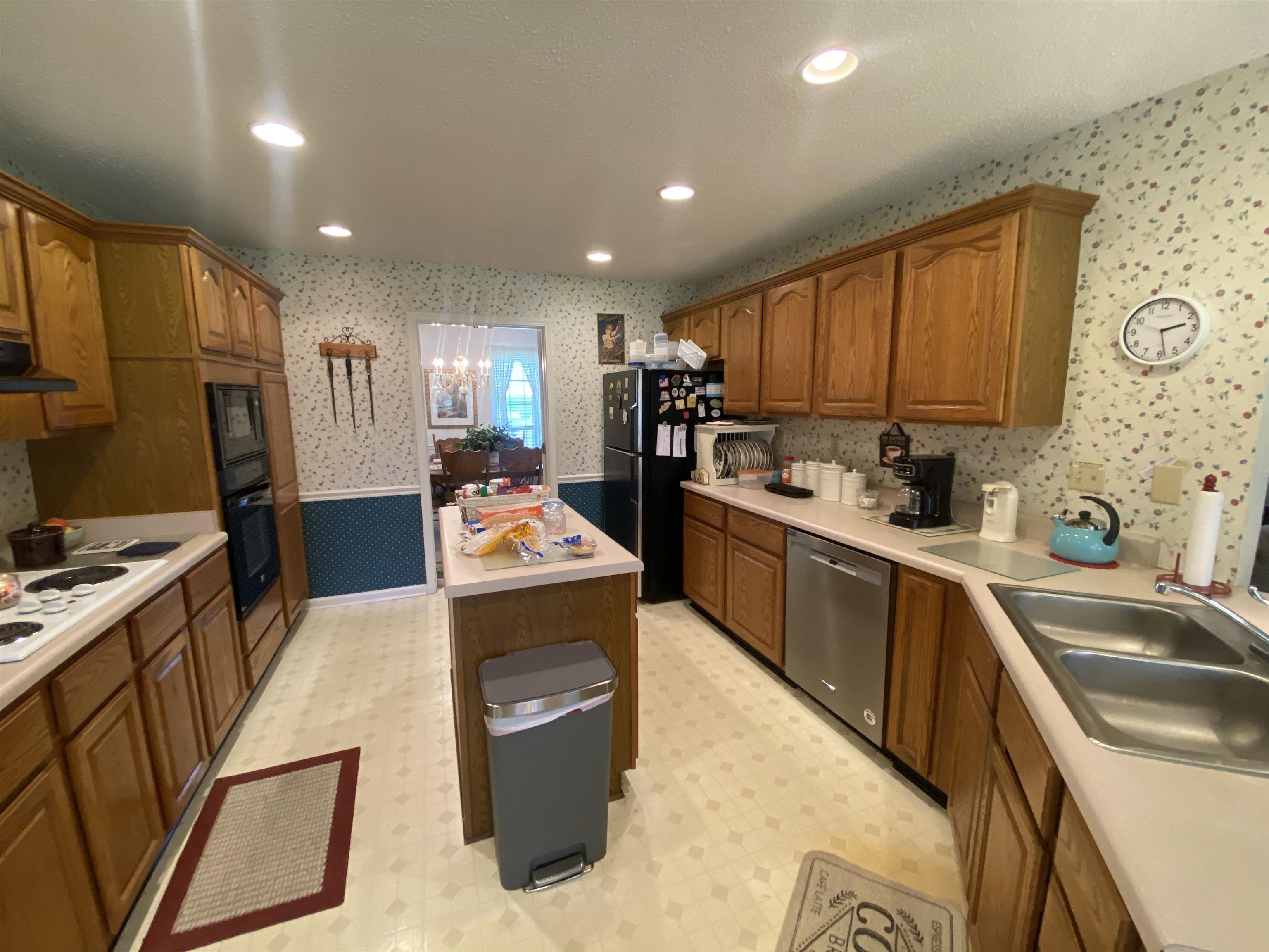 240 Sawmill Road Brighton, TN 38011 - Photo 15 of 25 Kitchen featuring black appliances, wallpapered walls, a sink, ventilation hood, and brown cabinetry