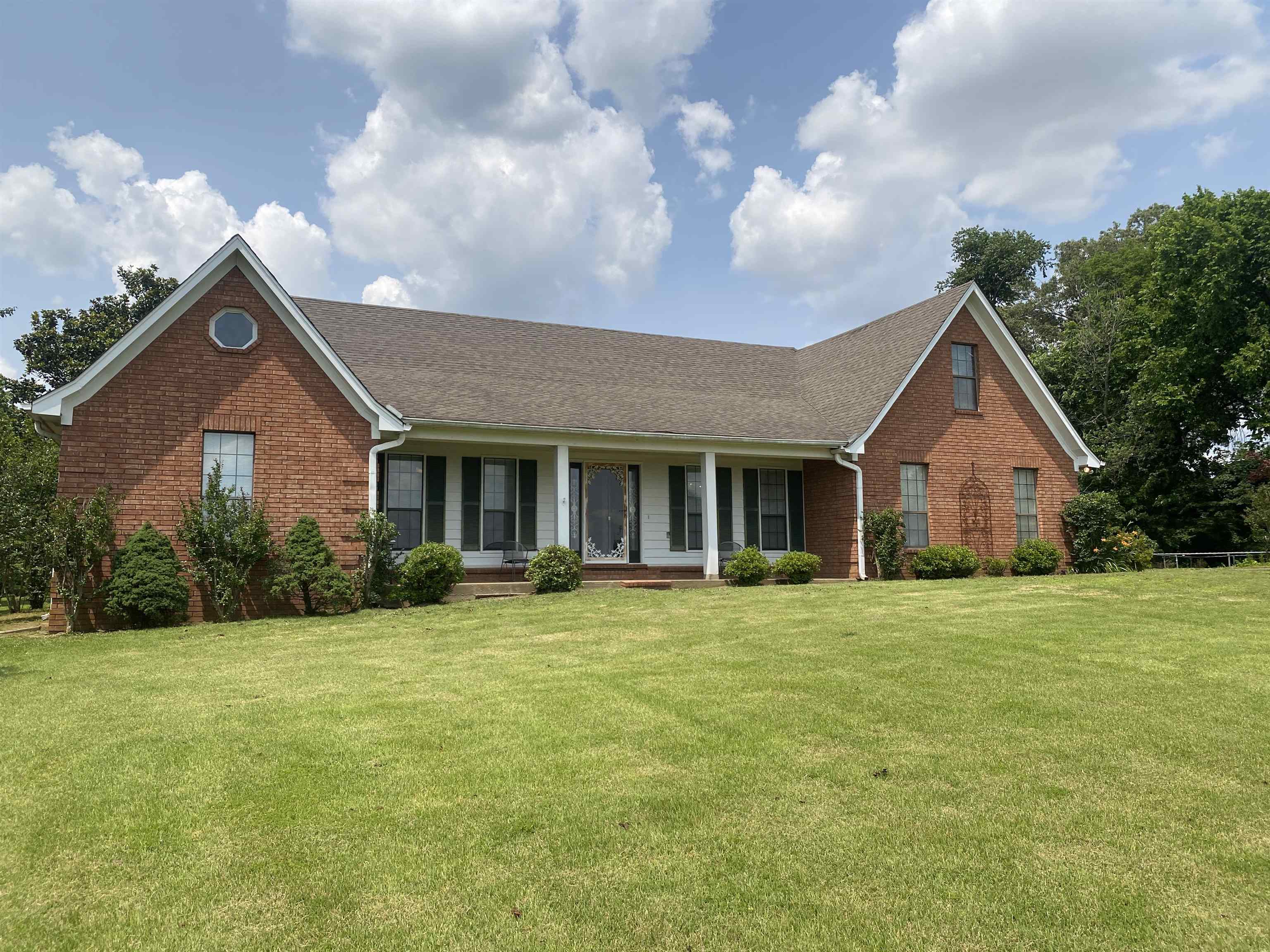 240 Sawmill Road Brighton, TN 38011 - Photo 2 of 25 Traditional-style house featuring a porch, brick siding, a front lawn, and roof with shingles