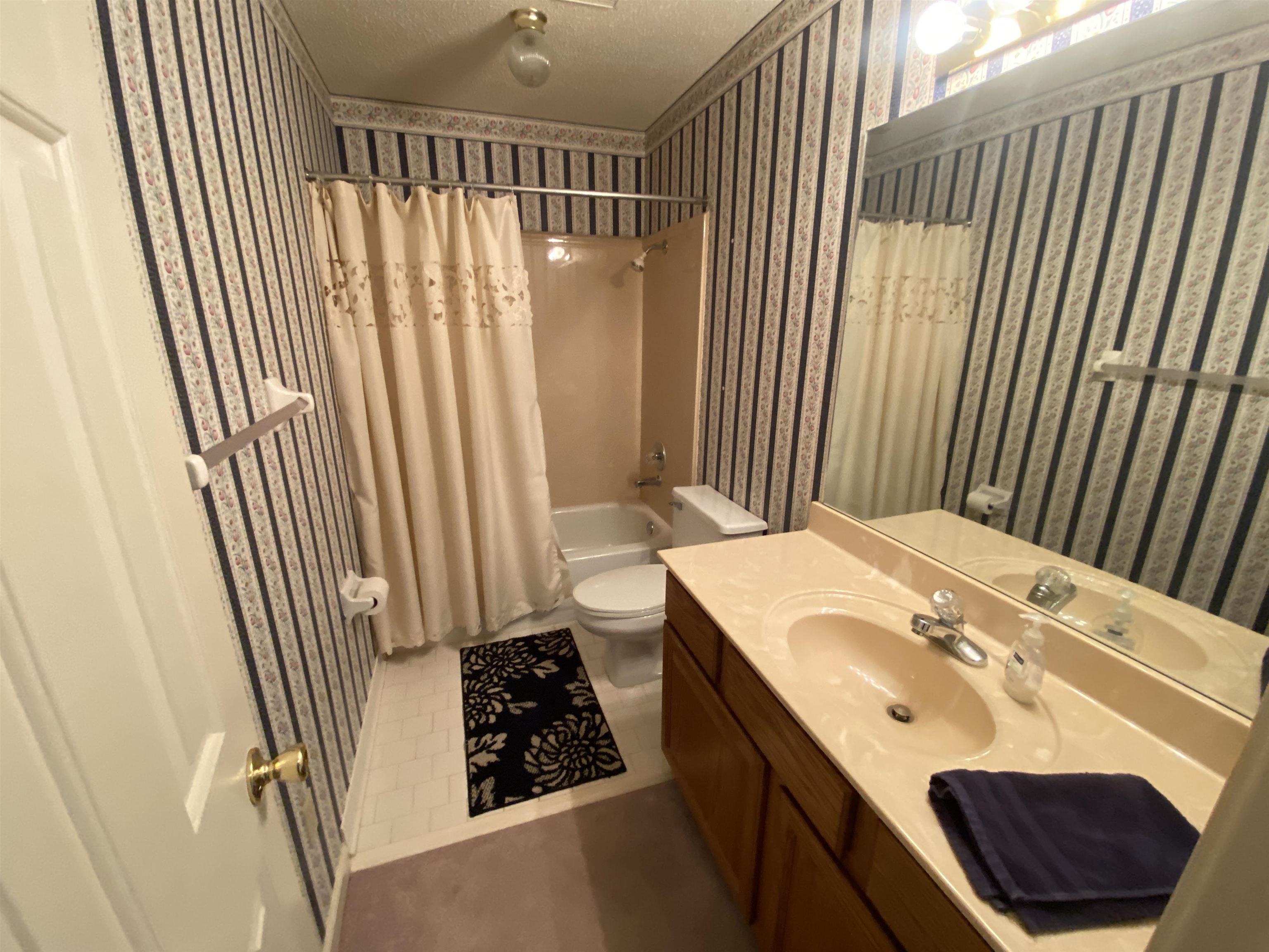 240 Sawmill Road Brighton, TN 38011 - Photo 22 of 25 Bathroom with wallpapered walls, vanity, toilet, shower / bath combo, and a textured ceiling