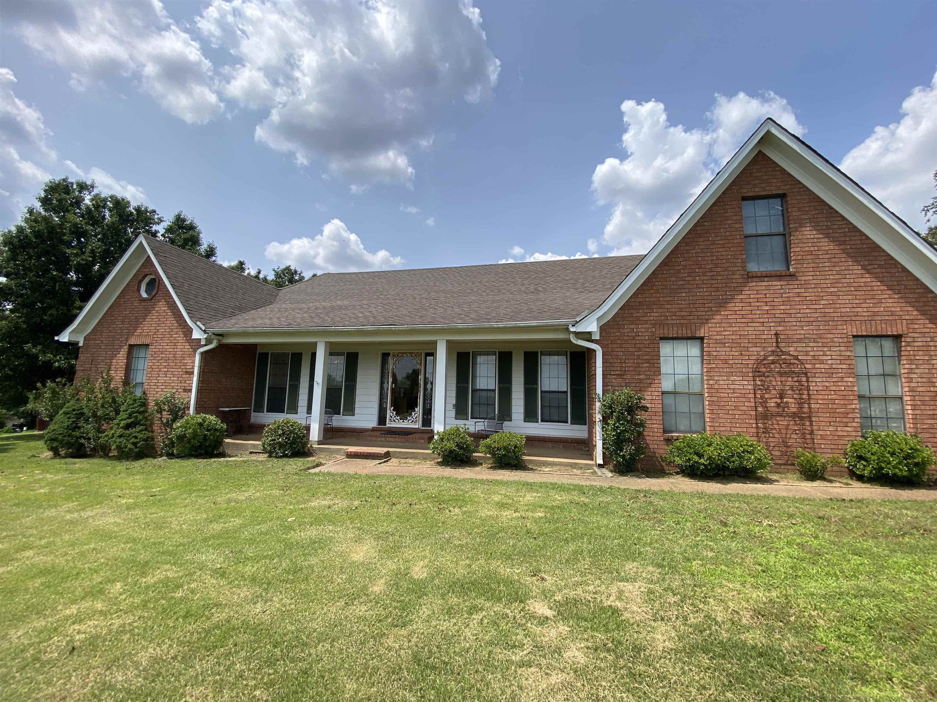 240 Sawmill Road Brighton, TN 38011 - Photo 3 of 25 View of front of house with brick siding, covered porch, a front yard, and a shingled roof