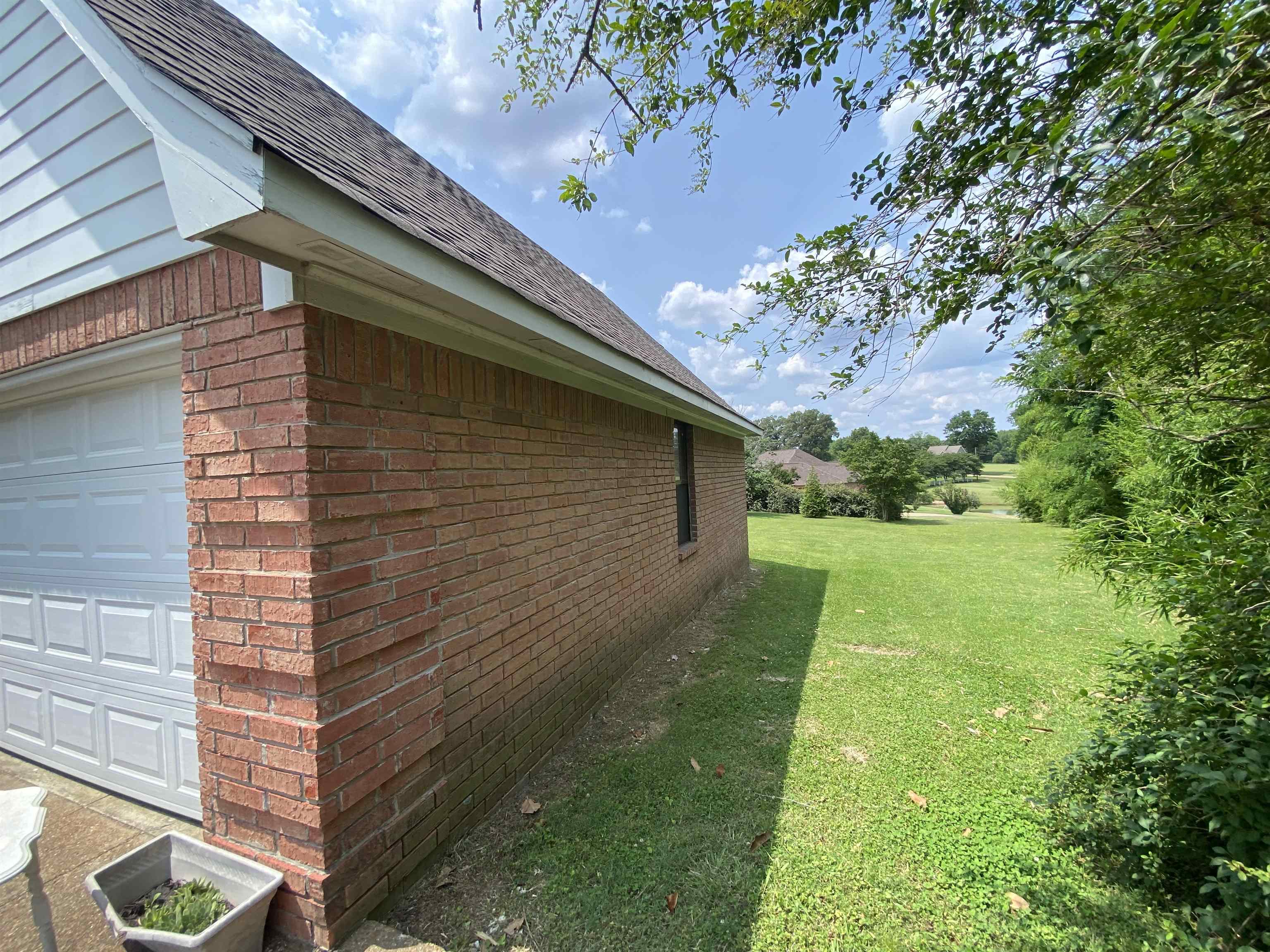 240 Sawmill Road Brighton, TN 38011 - Photo 8 of 25 View of home's exterior featuring brick siding, a lawn, a garage, and a shingled roof
