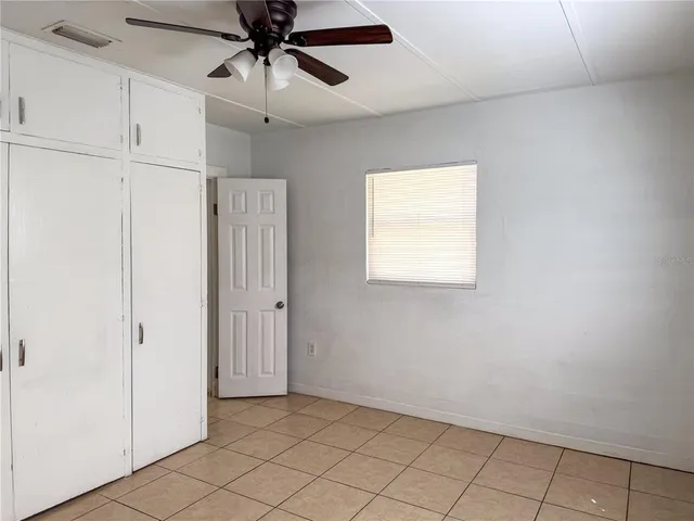 a view of an empty room and chandelier fan