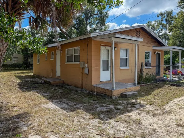 a view of a small house with yard and tree in front of it