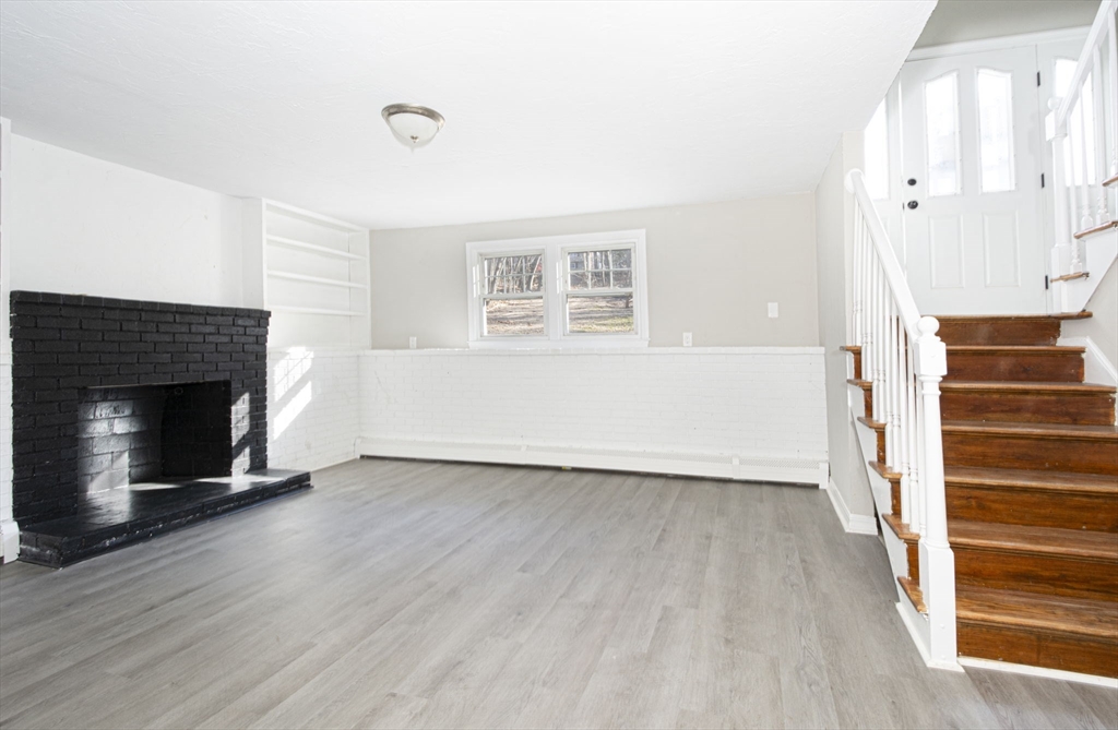 55 Dodge Road Sutton, MA 01590 - Photo 24 of 35 an empty room with wooden floor fireplace and windows
