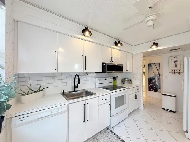 a kitchen with white cabinets and appliances