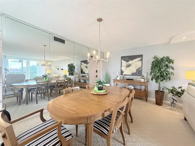 a view of a dining room and livingroom with furniture wooden floor a chandelier