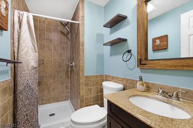 a bathroom with a granite countertop sink toilet a mirror and shower
