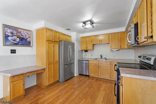 a kitchen with a refrigerator a stove cabinets and wooden floor