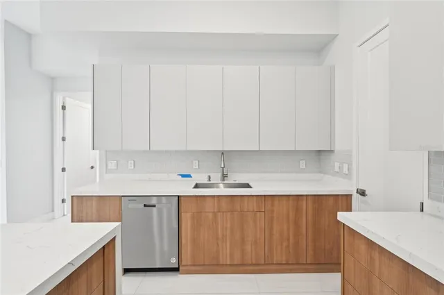 a large kitchen with stainless steel appliances a sink a stove a refrigerator and a cabinets