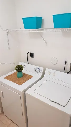 a living room with stainless steel appliances furniture a flat screen tv and kitchen view