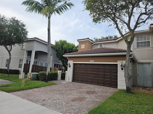 a front view of a house with a garden and trees