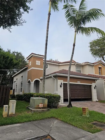 a view of a white house with a yard and potted plants