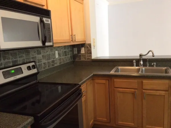 a kitchen with stainless steel appliances granite countertop a sink a stove and a microwave