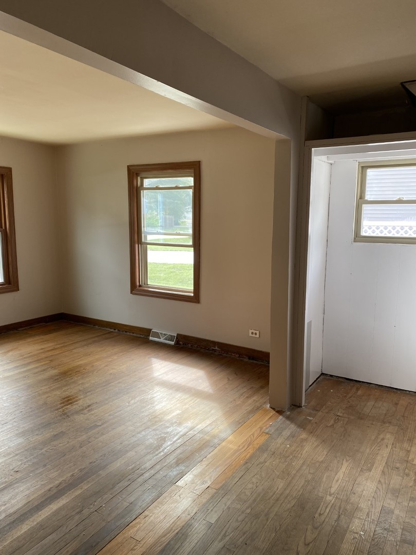 242 Highland Road Willowbrook, IL 60527 - Photo 5 of 24 a view of an empty room with wooden floor and a window