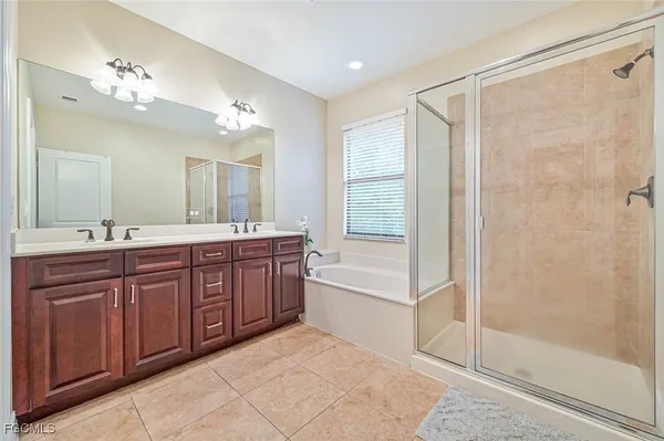 a spacious bathroom with a granite countertop sink a mirror a shower and a bathtub