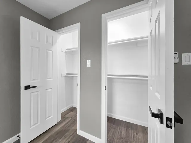 a view of an empty room with window and wooden floor