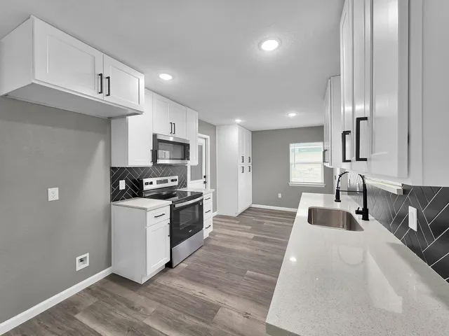 a kitchen with stainless steel appliances granite countertop a sink a stove and a refrigerator