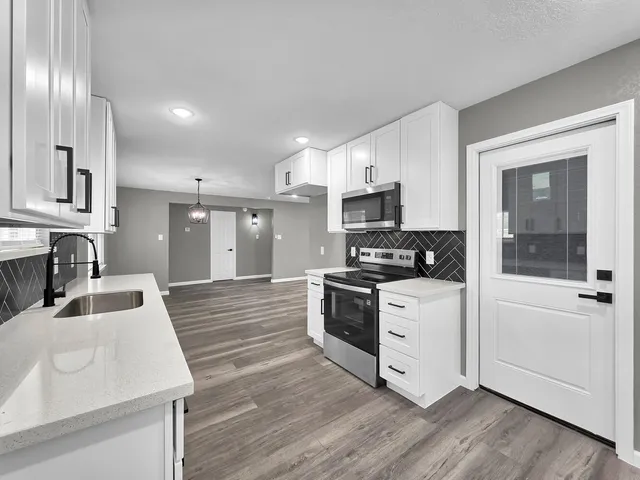 a kitchen with stainless steel appliances granite countertop a sink a stove and a refrigerator