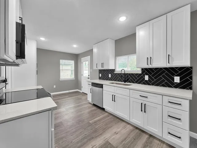 a kitchen with granite countertop white cabinets and black appliances