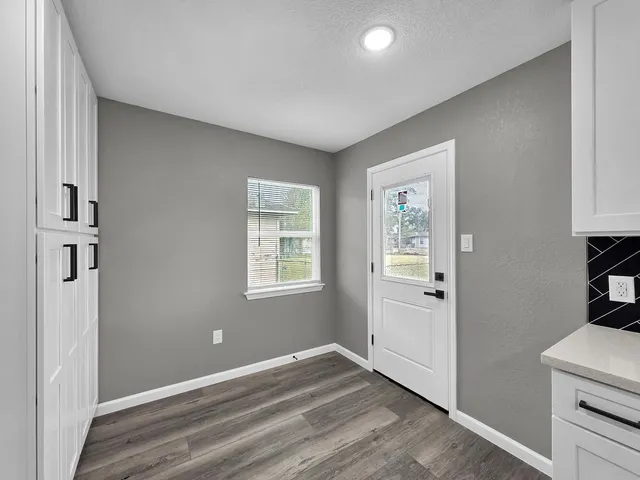 a view of an empty room with window and wooden floor