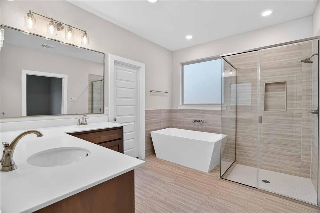 321 Skeen Peak Springtown, TX 76082 - Photo 35 of 37 Contemporary bathroom featuring a freestanding tub, a walk-in shower with clear glass enclosure, dual vanity with undermount sinks and quartz countertops, and neutral-toned wall and floor tiling