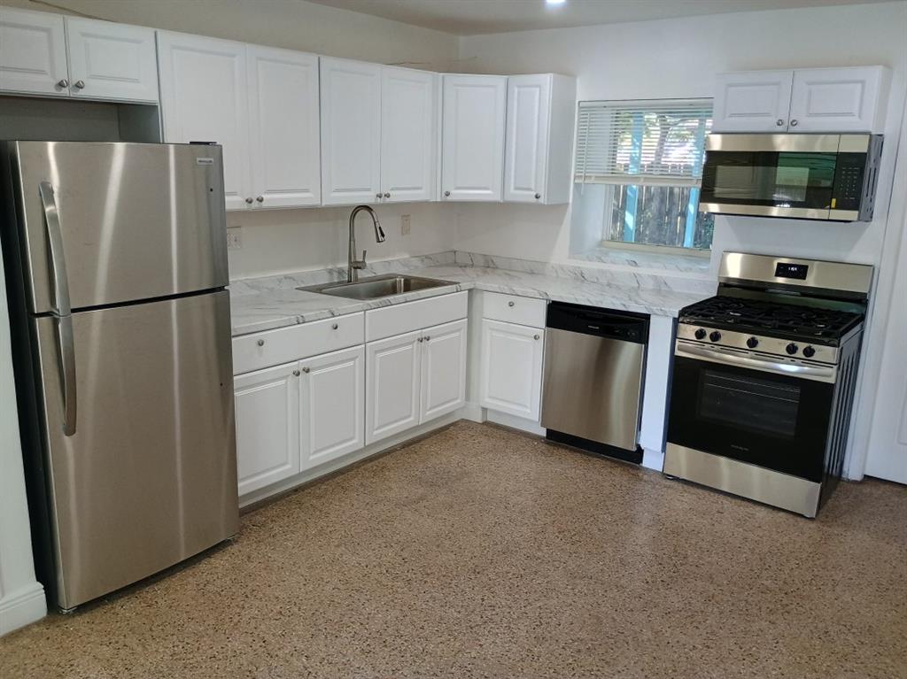 2465 Northeast 14th Avenue Pompano Beach, FL 33064 - Photo 2 of 6 a kitchen with stainless steel appliances granite countertop a refrigerator stove a sink and a microwave