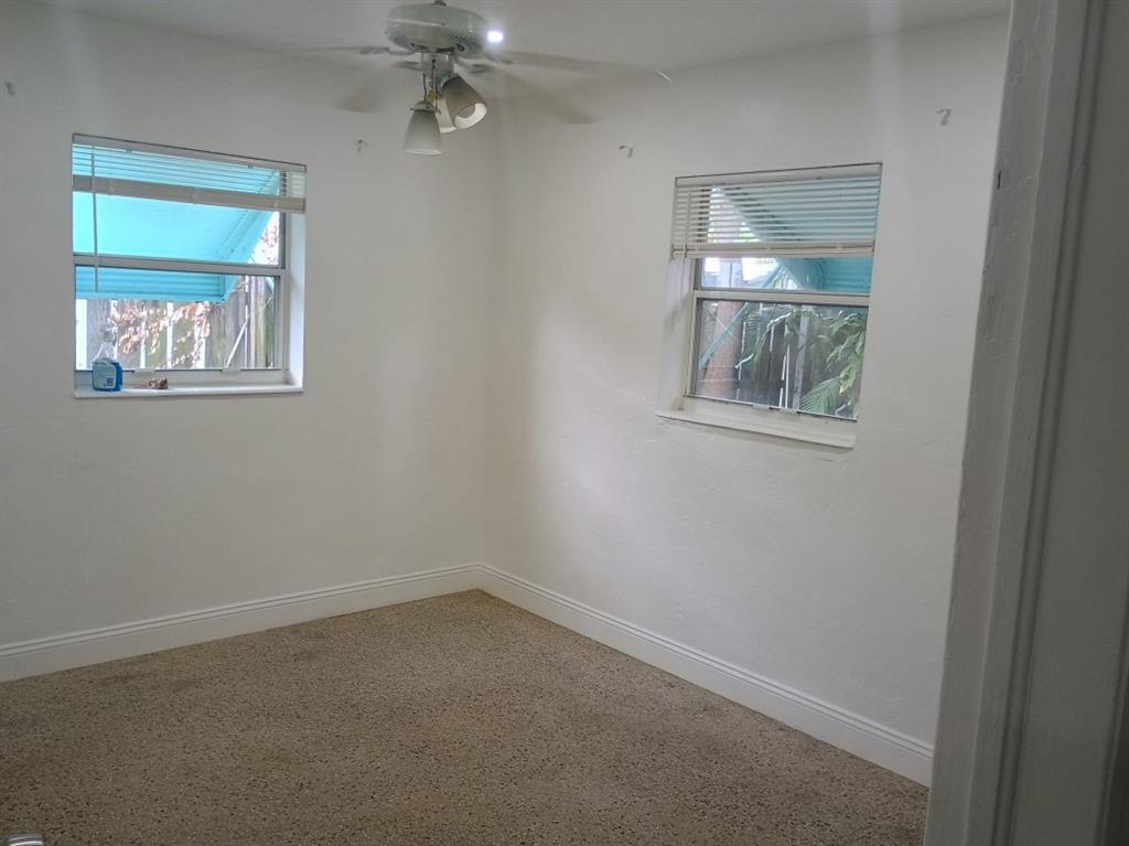 2465 Northeast 14th Avenue Pompano Beach, FL 33064 - Photo 3 of 6 an empty room with a chandelier fan and windows