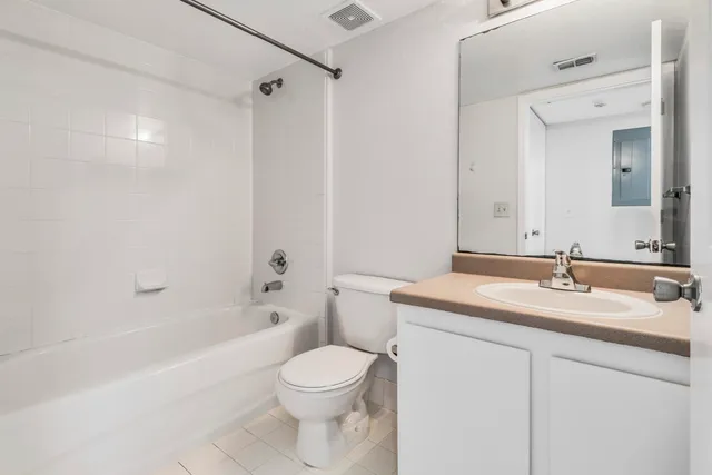 a bathroom with a bathtub shower sink vanity mirror and toilet