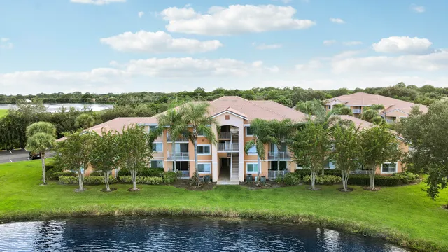 a view of a big house with a big yard and potted plants and large trees
