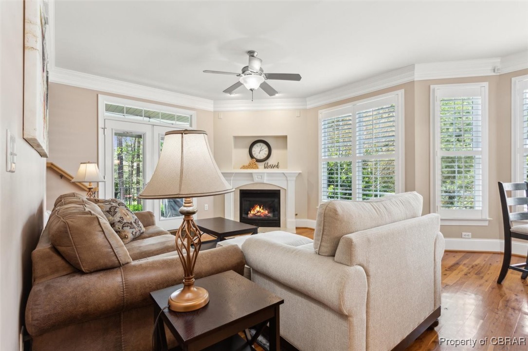 3013 Ridge Drive Toano, VA 23168 - Photo 15 of 50 Living room with a warm lit fireplace, wood finished floors, ornamental molding, baseboards, and ceiling fan