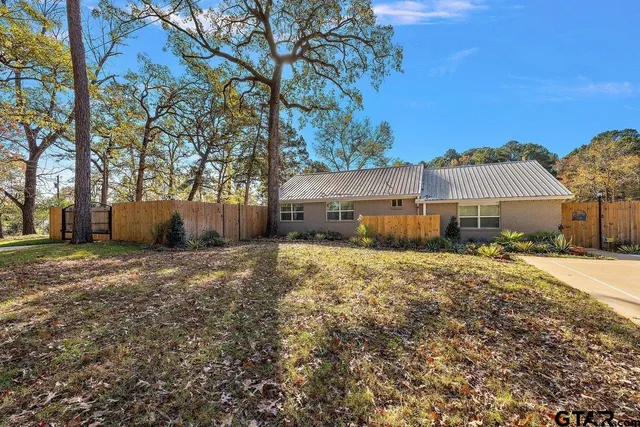 a backyard of a house with wooden fence and a large tree