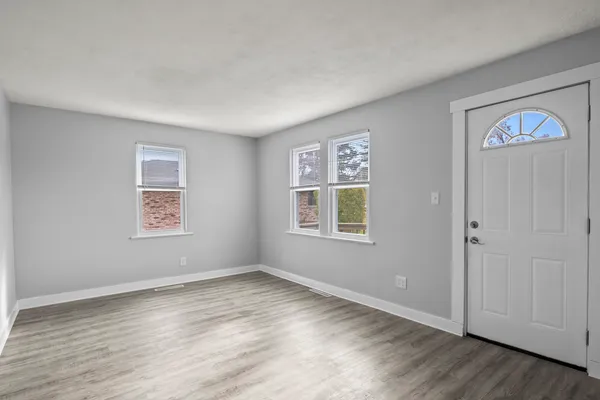 a view of an empty room with window and wooden floor