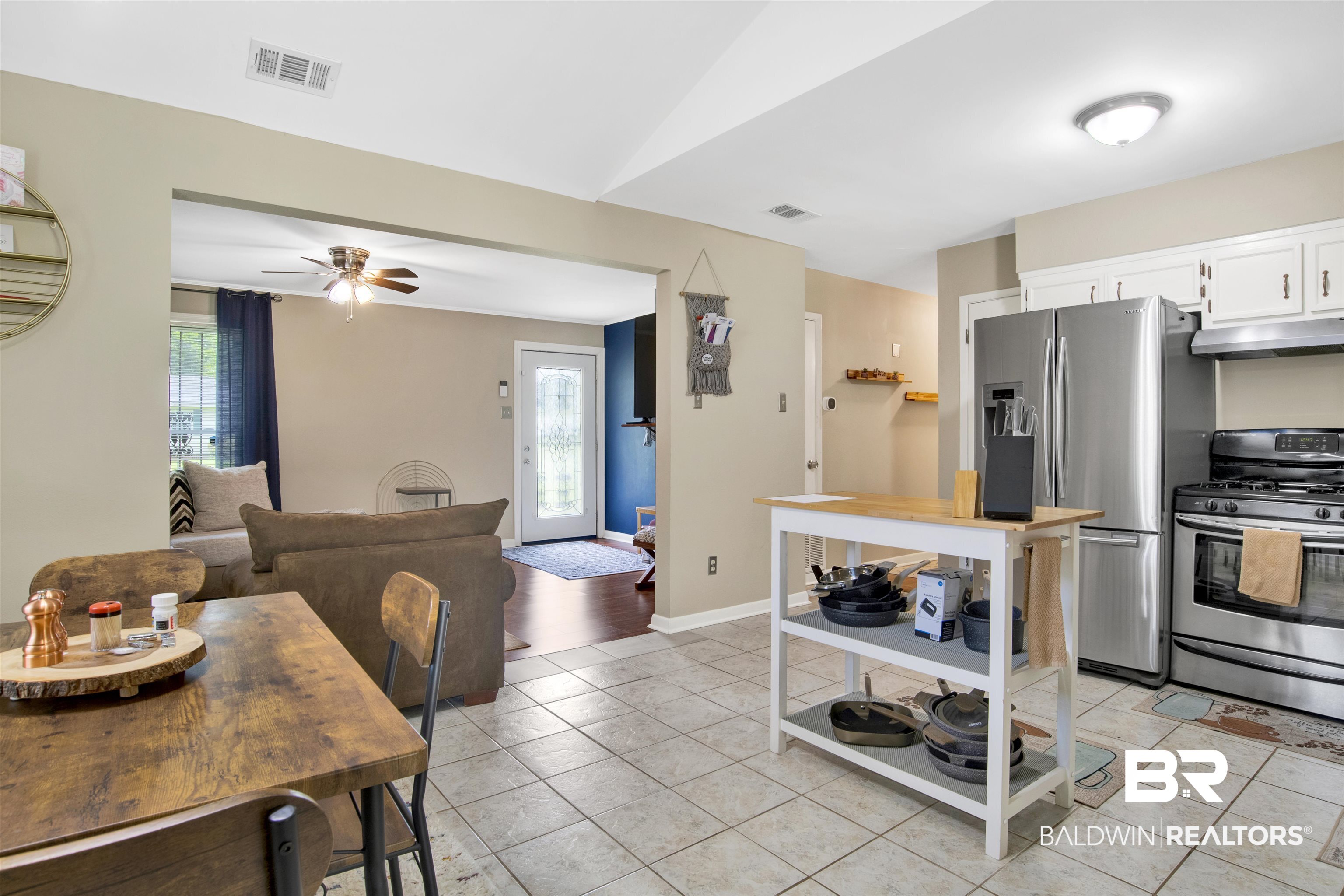1476 Boudousquie Street Mobile, AL 36605 - Photo 12 of 34 Kitchen with stainless steel appliances, exhaust hood, light tile patterned floors, white cabinetry, and a ceiling fan